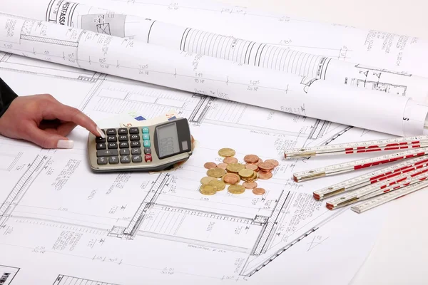 Hands with house construction plan, calculator, money, coins