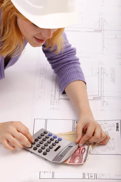 Happy woman with blueprint, helmet, calculators, money