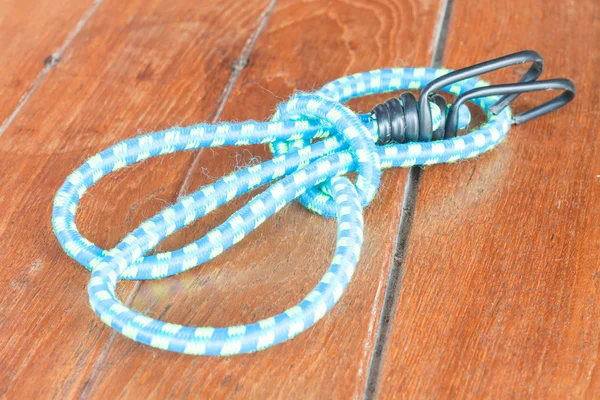 Light blue elastic rope on wood background