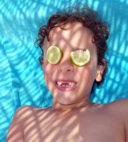 Boy grinning with two lemon slices on his eyes
