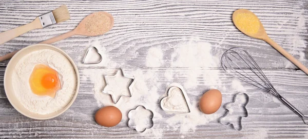 Ingredients and molds for baking cookies on wooden background