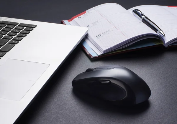 Laptop, mouse and the diary on the table