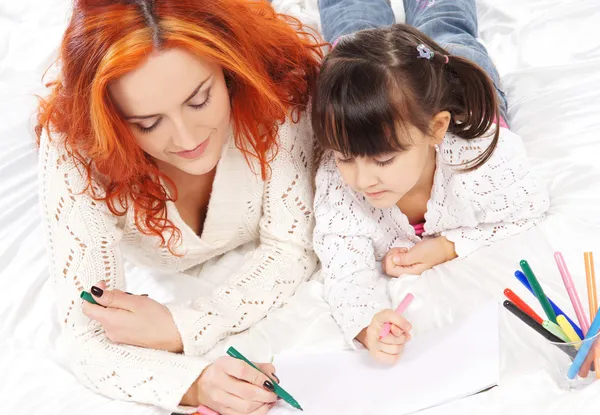 A happy mother and a little daughter drawing with markers