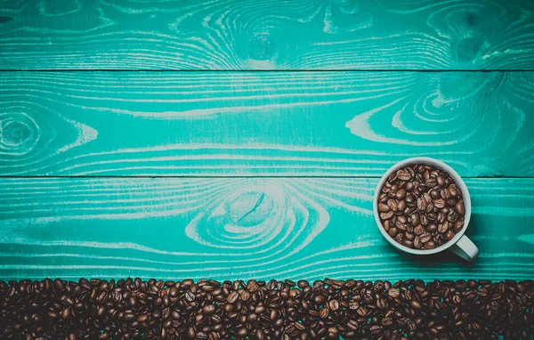 Beautiful white coffee cup with coffee beans on turquoise wooden Toned in warm colors