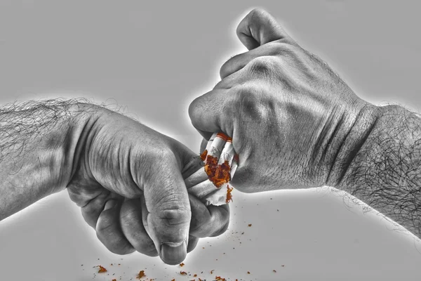 Human hands violently breaking cigarettes