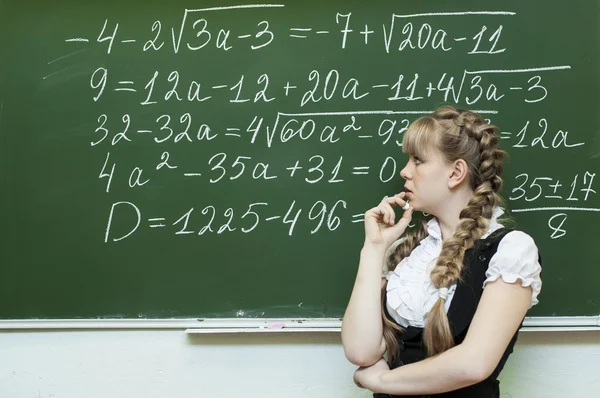 Schoolgirl at the blackboard writes — Stock Photo #39562021