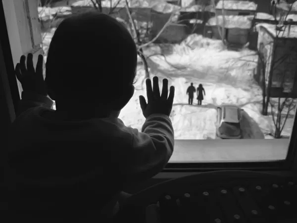 Black and white photo small child looking out the window.