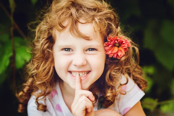 Beautiful little girl putting finger up to lips and ask silence.