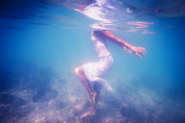 Underwater woman portrait with white dress into the sea.