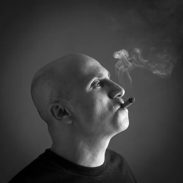 Man smoking cigar portrait on dark background. Black and white i