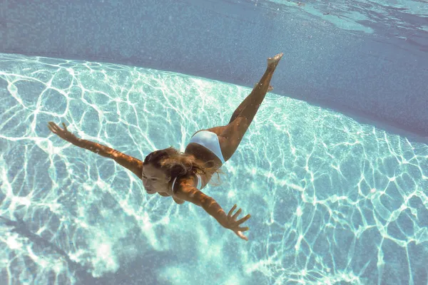 Underwater womportrait with white bikini in swimming pool.