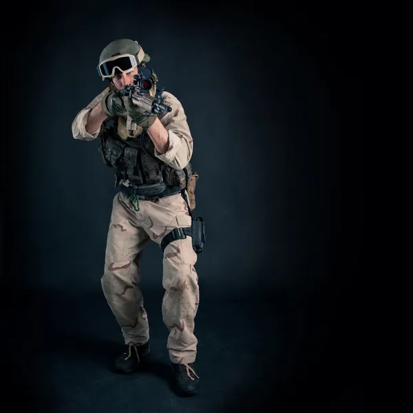 Soldier with rifle against black background. Full body and copy