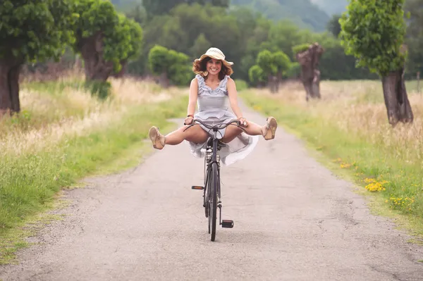 Pretty young woman riding bike in a country road Stock Image