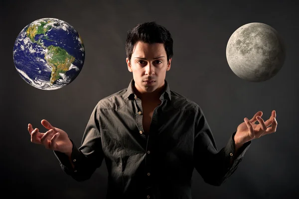 Young man showing hands as a magician with earth and moon