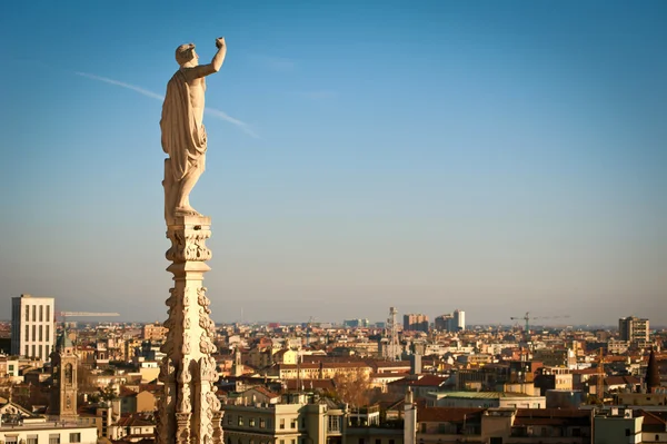 Gothic spire on the roof of Milan Dome with city landscape as background