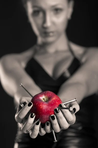 Conceptual image of beautiful girl with nails driven apple. Shallow depth of field