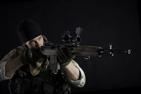 Soldier with rifle against black background