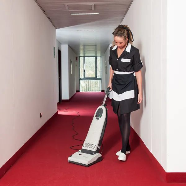 Chambermaid woman cleaning in a hotel with vacuum cleaner