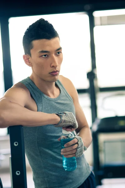 Young asian man having a rest drinking a beverage in the gym. — Stock Photo #21629317