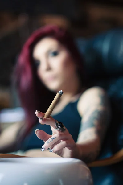Red head girl with tattoo smoking cigar, shallow dof.