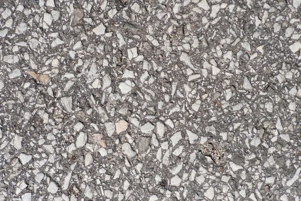 Old asphalt road with big grain stones.