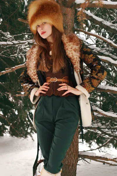 Beautiful girl in winter on Christmas. Fashion and beauty. Style of designer clothes. Warm fur and Russian traditions in the evening on the farm.