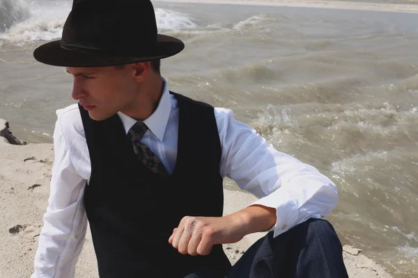 Beautiful brutal man in a classic suit. Cowboy in the desert near the river water. Fashion and Beauty. Black and white in nature