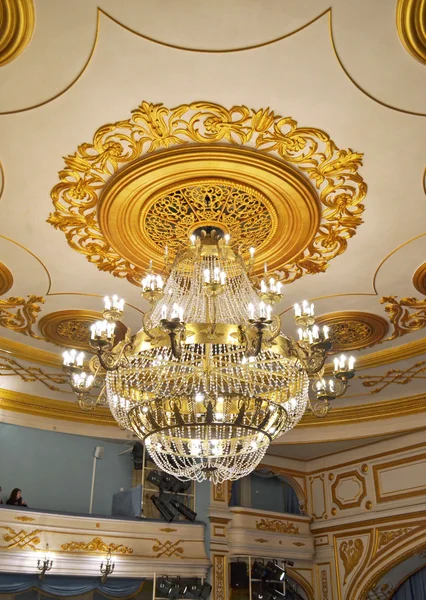 Crystal chandelier and gilded stucco moldings on the ceiling of drama theater in the city of Irkutsk