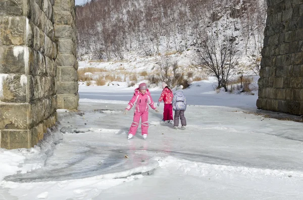 Little girls skate on Baikal ice under the viaduct