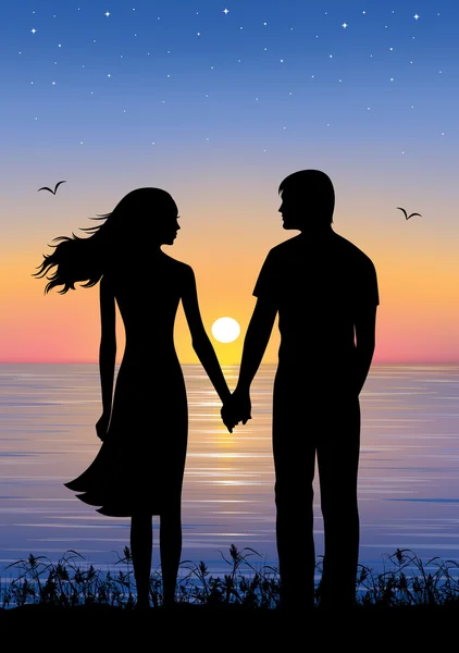Silhouettes of man and woman standing and holding hands at evening time. On the background sunset and stars over the sea.