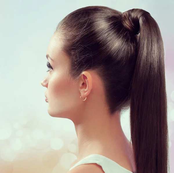 Young female with healthy shining brown hairs put in pony tail.