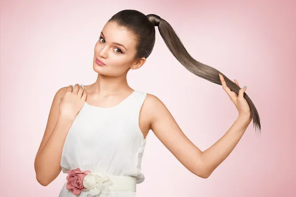 Young femail with healthy shining brown hairs put in pony tail.