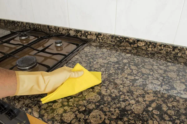 Woman cleaning kitchen with yellow cloth