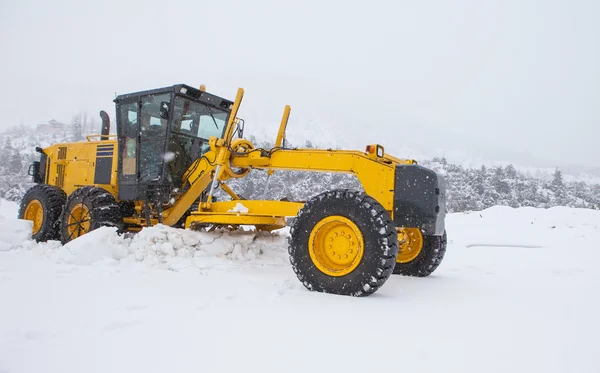 The bulldozer cleans snow on road