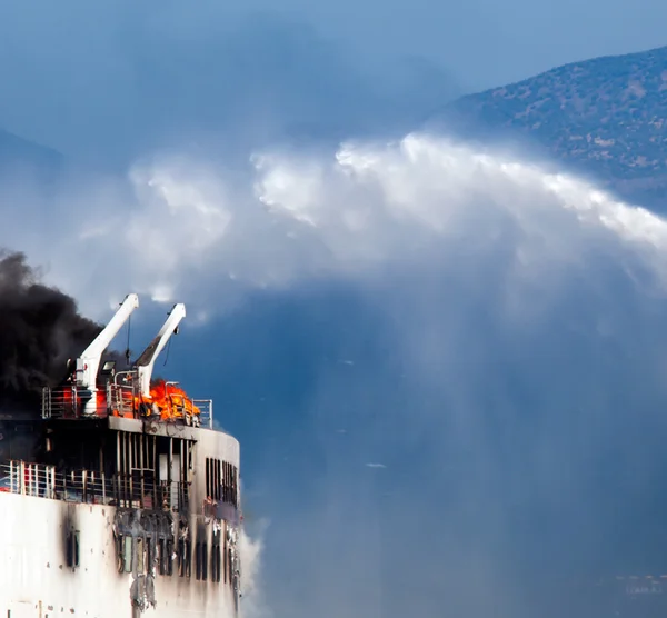 Burning ship and Fire Fighting Boat sprays jets of water