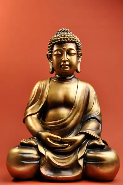 Bronze Buddha Statue Against a Red Orange Background