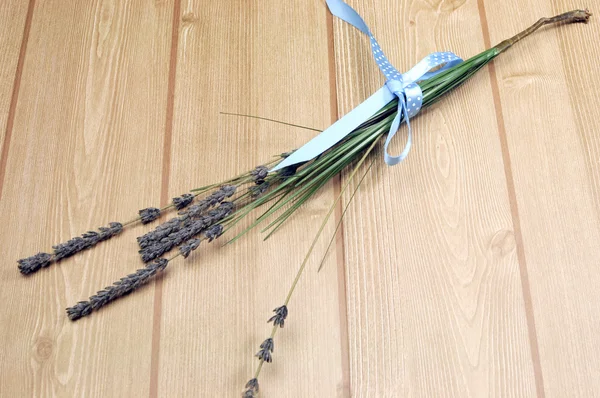Sprigs of Lavender flower tied in blue polka dot ribbon for aromatherapy, health or herbal bouquet, on wood table..