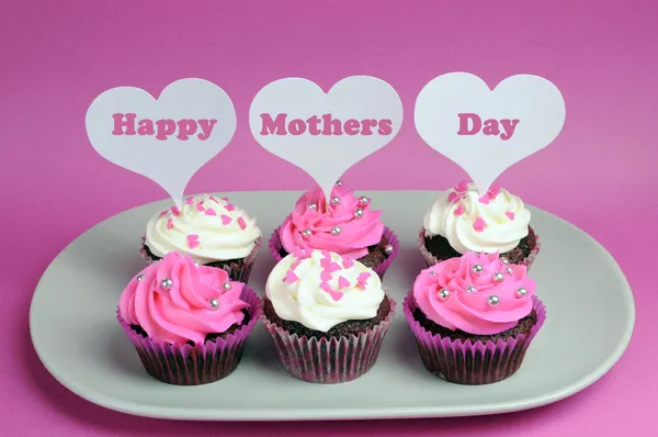 Happy Mother's Day message across white heart toppers on pink and white decorated red velvet cupcakes