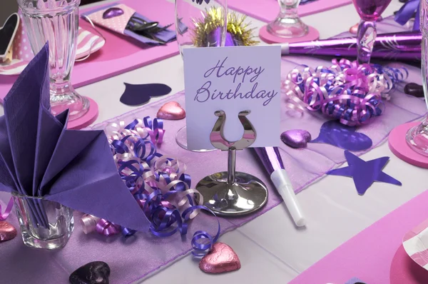 Pink and purple theme party table setting decorations with Happy Birthday message on table stand.