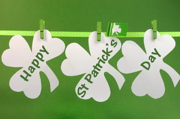 Celebrate St Patricks Day holiday on March 17 with Happy St Patricks Day message greeting written across white shamrocks hanging from pegs on a line