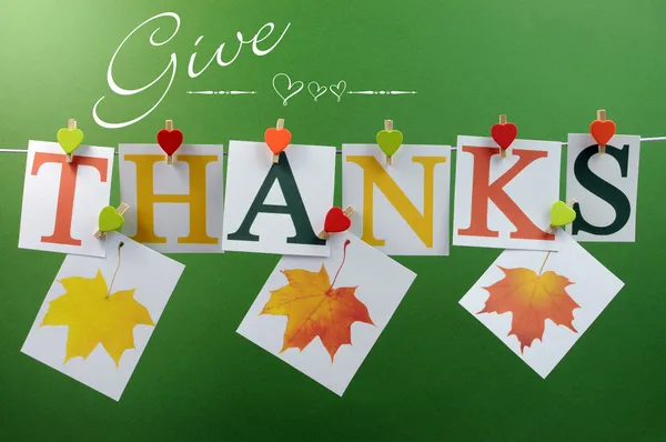 Give Thanks message across pegs on a line for Happy Thanksgiving greeting with hanging leaves