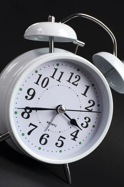 Classic white alarm ticking clock on black background
