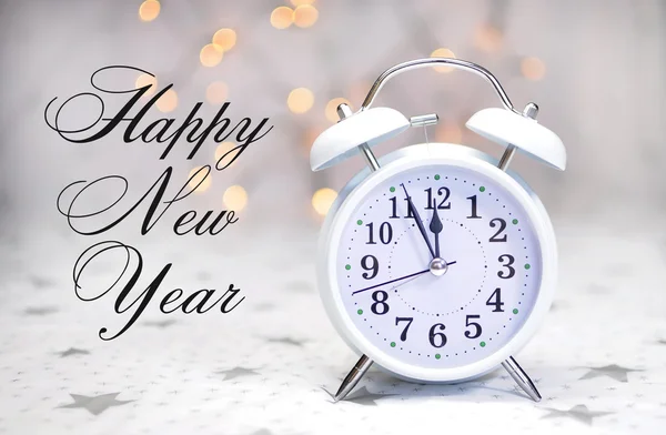 Happy New Year message with white retro clock showing five to midnight