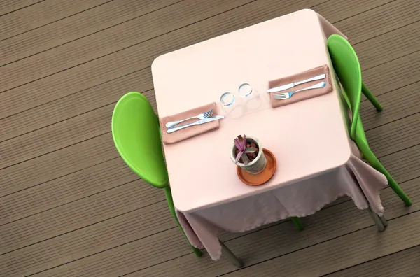 Dining table with pink tablecloth and green chairs and plant