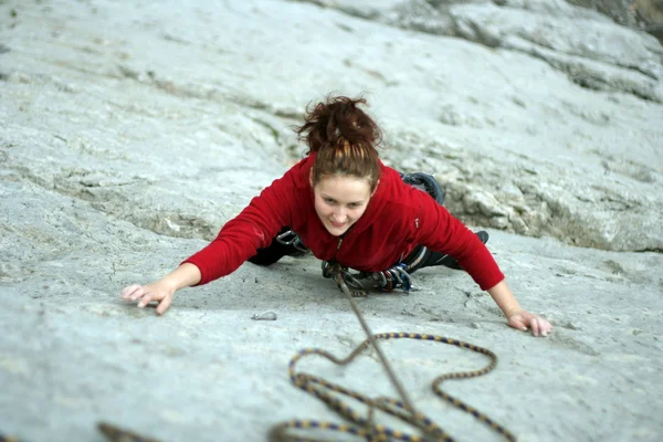 Young woman climbing on a limestone wall with wide valley