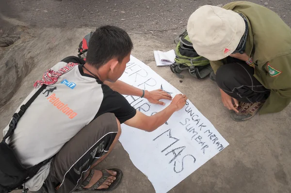 Indonesian students write poster for pictures on the top of Volc