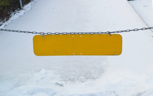 Blank yellow plate on chains on snow background