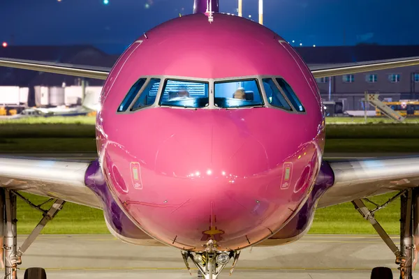 Close up of the nose of a violet airbus parked at night.