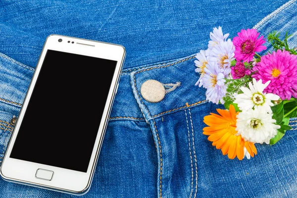 Mobile phone in pocket of blue jeans with flowers