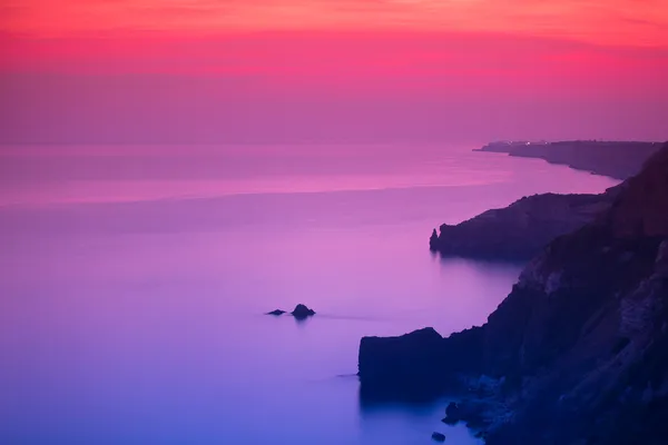 Purple and pink sunset over ocean shore